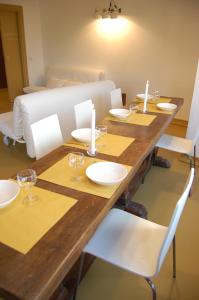 - une grande table en bois avec des assiettes blanches et des bougies dans l'établissement Casa accanto al Vaticano, à Rome
