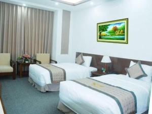 a hotel room with two beds and a chair at Draco - Thang Long Hotel in Hai Phong +59 photos