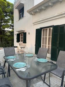 a table with plates and glasses on a patio at Villa Rhodos Skiathos in Skiathos