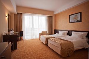 a hotel room with a large bed and a window at Hotel Clermont in Covasna