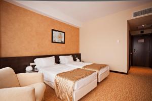 a hotel room with a large bed and two chairs at Hotel Clermont in Covasna