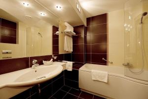 a bathroom with a sink and a shower and a tub at Hotel Clermont in Covasna
