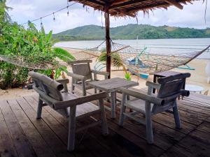 a table and chairs and a hammock on a beach at Amwani Beach Camp - Mini Glamping Tent in El Nido