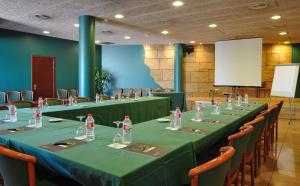 una sala de conferencias con mesas y sillas largas y una pantalla en Hotel Els Noguers, en Manresa