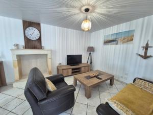 a living room with a couch and a table and a clock at La plage et le calme in Marennes