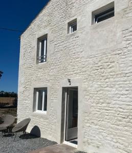 马雷讷La plage et le calme的一座白色石头建筑，前面放着两把椅子。 更多35张照片