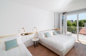 a white bedroom with a bed and a balcony at Residence Ten Suite in Rimini