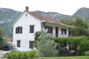 a white house with mountains in the background at Apartments Niković in Risan