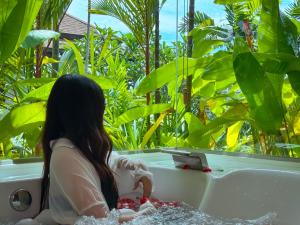 a woman sitting in a bathtub in a garden at Villa Tantawan Resort - Private Pool Villas in Kamala Beach