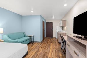a bedroom with a bed and a couch and a television at WoodSpring Suites Richmond Airport in Henrico