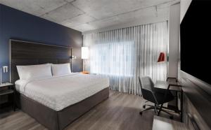 a bedroom with a bed and a desk and a television at Tru By Hilton Montréal centre-ville in Montréal