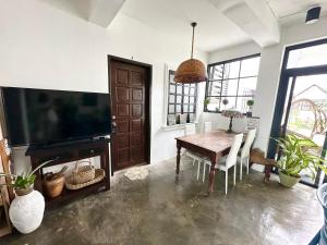 a dining room with a table and a flat screen tv at BACKDOOR VILLA in Baler
