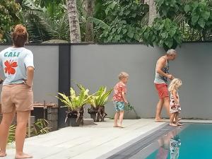 ゴールにあるGreen villaのスイミングプールの横に立つ男と子供2人