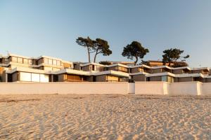 a building on the beach with trees in the background at Suite Deluxe Samil in Vilamar