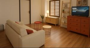 a living room with a white couch and a tv at Les remparts in Ensisheim