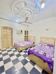 two beds in a room with a checkered floor at شقه للايجار اليومي او الشهري in Luxor