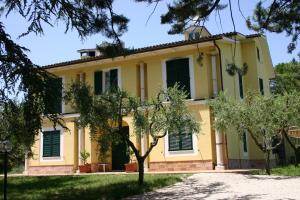 een geel huis met bomen ervoor bij Villa Poggio San Pietro in Mogliano