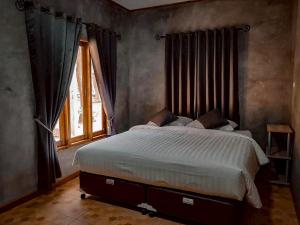 a bedroom with a large bed in front of a window at Phawaeng Resort พะแวงรีสอร์ท in Ban Noen Sabok