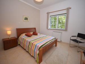 a bedroom with a bed and a window and a chair at Villa in Casais de Santa Helena in Carreiros
