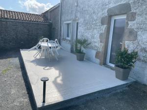 eine Terrasse mit Tisch und Stühlen und einem Fenster in der Unterkunft Maison en campagne in Mortagne-sur-Sèvre