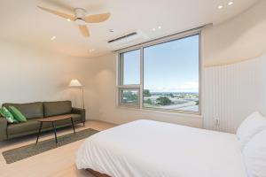 ein Schlafzimmer mit einem Bett und einer Couch und einem Fenster in der Unterkunft Aewol Damdam Stay in Sowang-dong