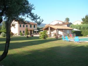 a yard with chairs and a house and a pool at Rustico del Chiasso - Villa With Private pool near Lucca in Lucca