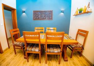 een eettafel en stoelen met een blauwe muur bij Homescapes in Kigali
