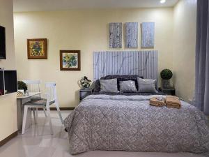 a bedroom with a bed and a table and a chair at Precious Ruby's Apartment in Manila