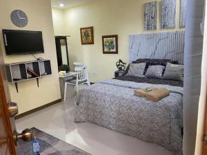 a bedroom with a bed and a flat screen tv at Precious Ruby's Apartment in Manila
