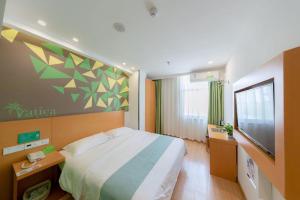 a bedroom with a large bed and a flat screen tv at Vatica Anhui Hefei South High Speed Rail Station Susong Road Hotel in Hefei