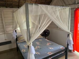 une chambre avec un lit à baldaquin dans l'établissement Le Rocher, sur l'île Sainte-Marie