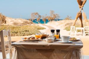 ein Tisch mit Frühstücksspeisen und Getränken an einem Strand in der Unterkunft Almiriki Naxos Beachside Living in Plaka