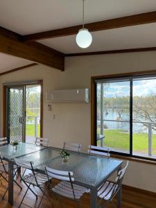 Un comedor con mesa y sillas y una gran ventana. en Golden Mile - On the Waterfront, en Bundalong