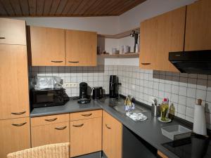 a kitchen with wooden cabinets and a black counter top at Ferienwohnung Schöntalweiher in Ludwigswinkel