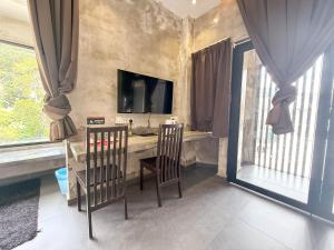 クアンタンにあるLE LODGE MANSIONの椅子2脚とテーブル1台とテレビがある部屋