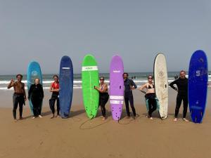 a group of people standing on the beach with their surfboards at Aourir Waves Surf House in Aourir