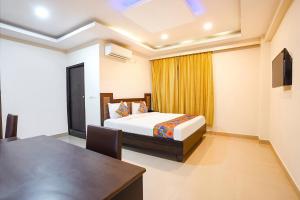 Un dormitorio con una cama y una mesa en una habitación. en FabHotel Millennium Suites - Millennium Plaza, Hosur Road, opp Vimalalaya Hospital, en Bangalore