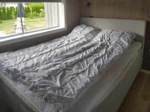 an unmade bed in a bedroom with a window at Stylish Cabin Experience In Beautiful Surroundings in Færvik