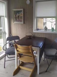 a dining room table with a chair and two windows at Stylish Cabin Experience In Beautiful Surroundings in Færvik