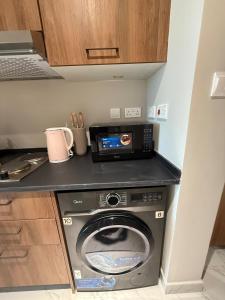 a kitchen with a washing machine and a microwave at The chic Retreat Stylish Studio 2 in Abu Dhabi