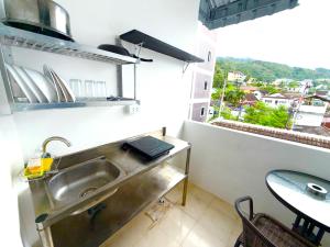 una cucina con lavandino, tavolo e finestra di Patong Canal Villa 302 a Patong Beach
