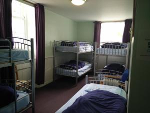 a room with four bunk beds and two windows at The Smugglers Hostel in Tomintoul