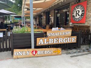 Un restaurante con carteles delante de un edificio. en Vagabond Vieiras Beds & Communal Dinner Albergue LE-210, en La Portela de Valcarce