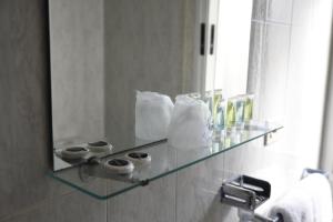 a bathroom with a glass shelf in front of a mirror at Hotel Villa De Ribadeo in Ribadeo