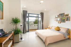 Un dormitorio con una cama y un escritorio y una ventana. en Homey Villa, en Da Lat