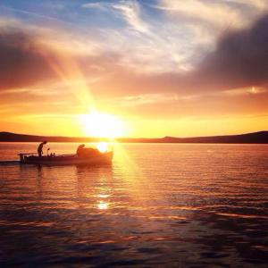 two people on a boat in the water at sunset at Apartment Eva in Maslenica