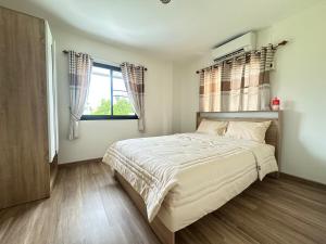 Un dormitorio con una cama grande y una ventana. en 2BR New renovation house in Phitsanulok, en Ban Khlong