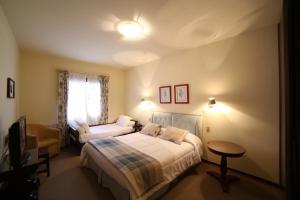 a bedroom with two beds and a chair and a television at Europa Hotel in Campos do Jordão