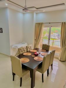 a dining room with a table and chairs and a window at Dahlia By T2R, 3BHK Bahria Town Phase 7, Close To DHA-1 Islamabad in Rawalpindi +13 photos