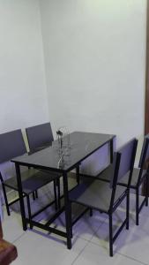 a black dining table and chairs with glasses on it at Apartment in Kigali